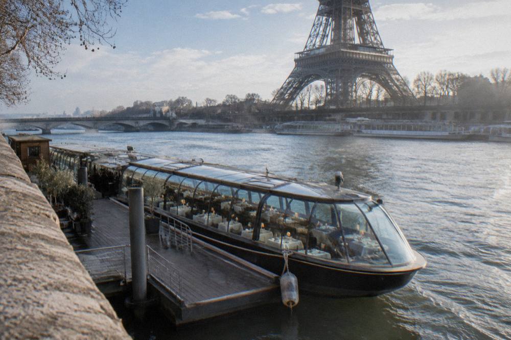 A glass-canopy cruise boat moored on the Seine near the Eiffel Tower in winter.