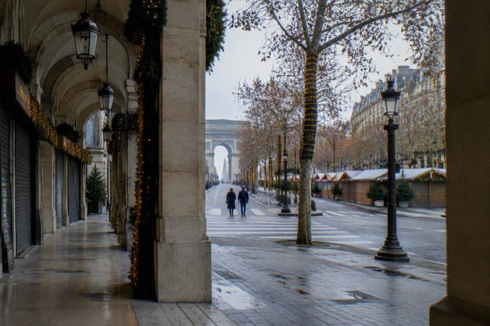 A wide Paris boulevard with holiday lights and almost no pedestrians on a December afternoon.