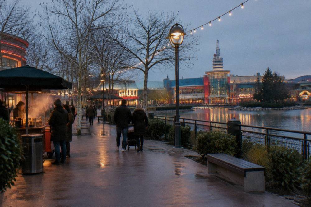 Decorated main street of a theme park with festive garlands and a large illuminated Christmas tree
