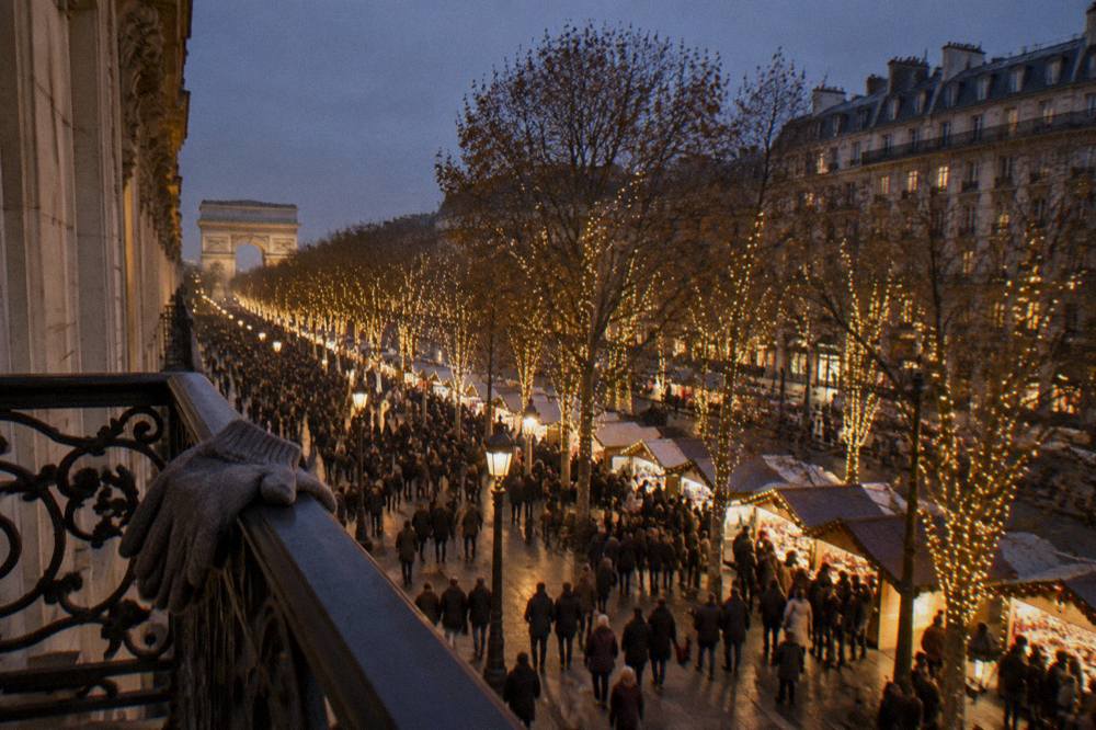 Crowded illuminated avenue at night with garlands of lights strung between trees
