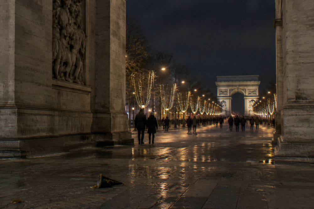 Wide avenue in Paris lined with illuminated trees and garlands glowing after dark