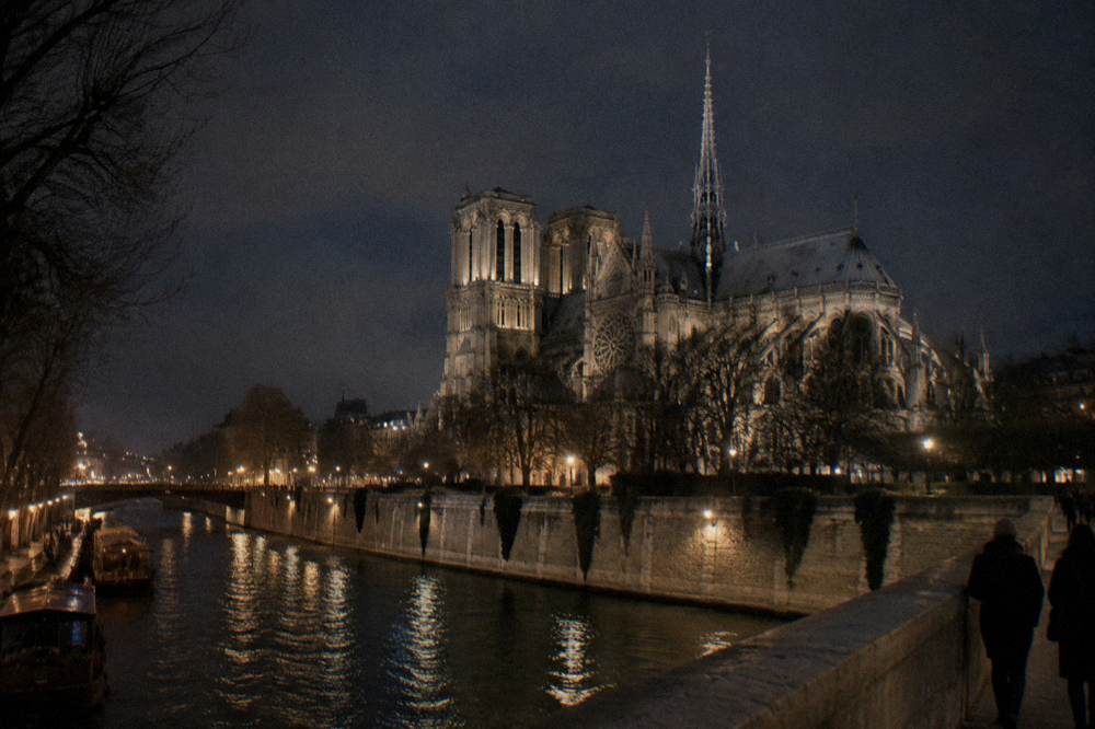 Ornate bridge over the Seine illuminated at night with warm street lamps along the banks