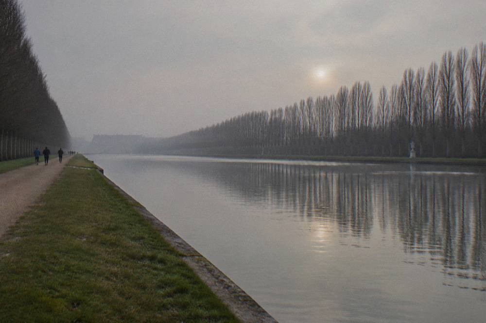 Golden gates of the Versailles palace under a grey December sky