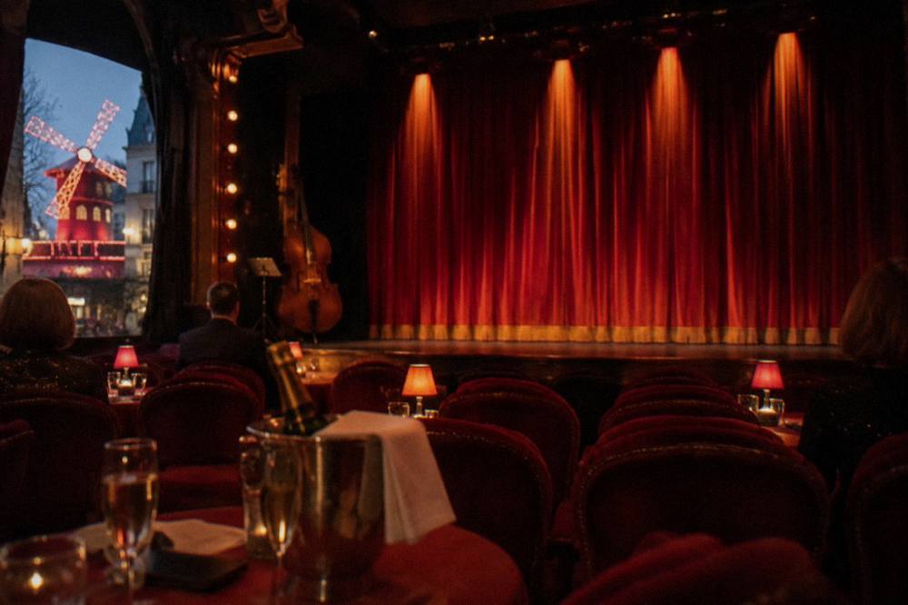 A cabaret stage with red velvet curtains and warm spotlights before a performance