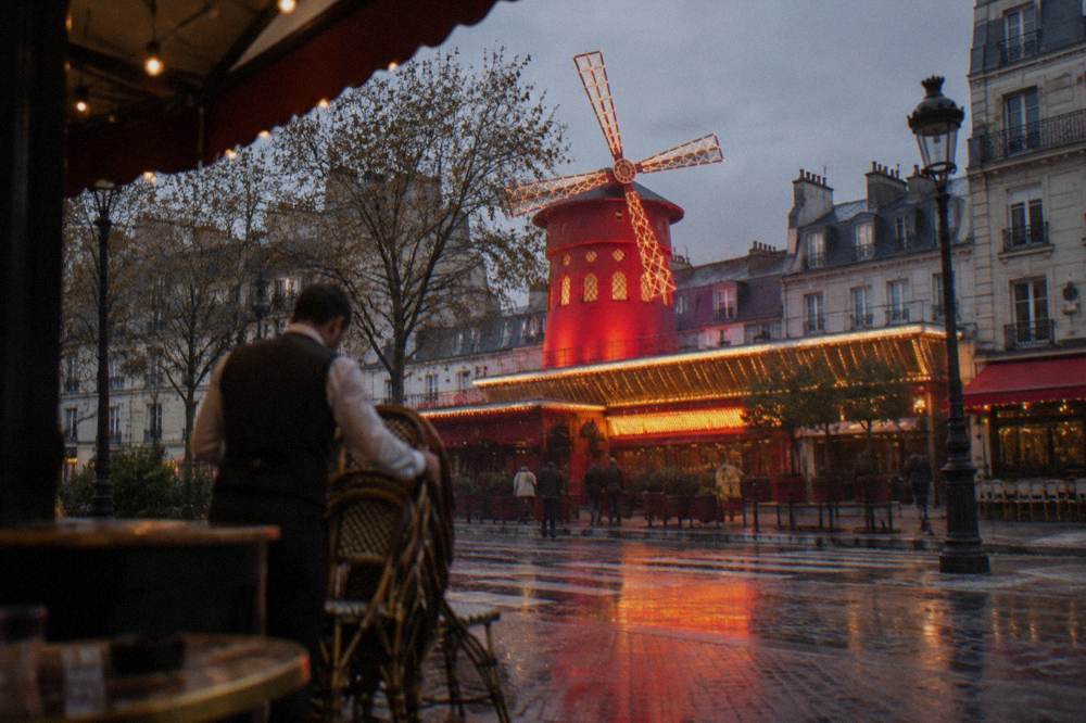 The lit exterior of a Paris theatre at dusk with a glowing marquee