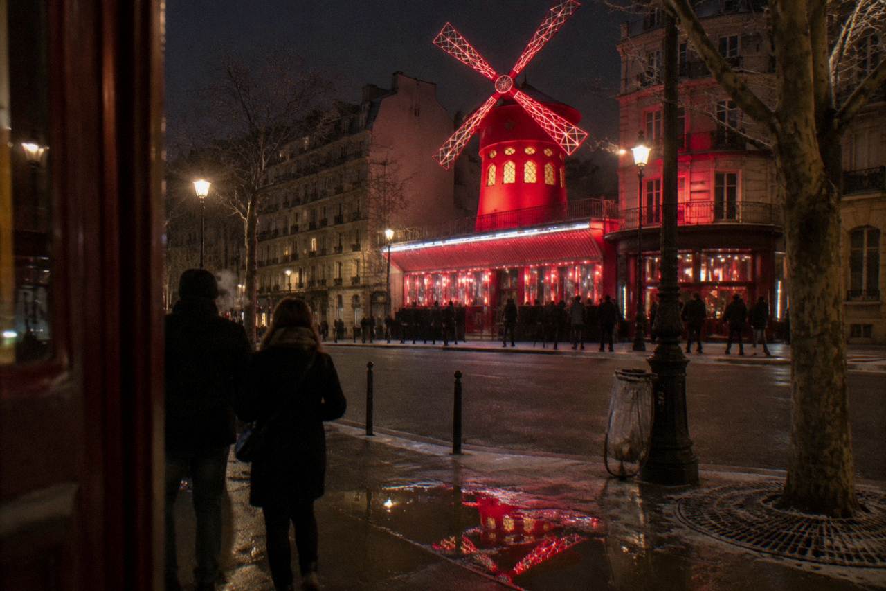 The illuminated windmill facade of a Paris cabaret building at night