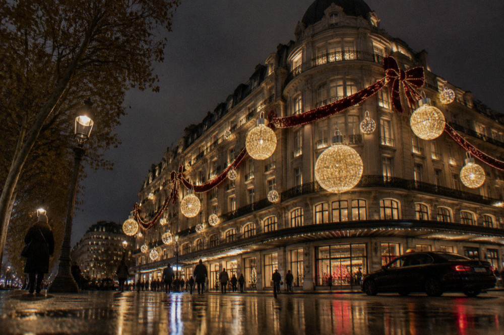 A department store facade decorated with glowing ornaments and ribbons at night