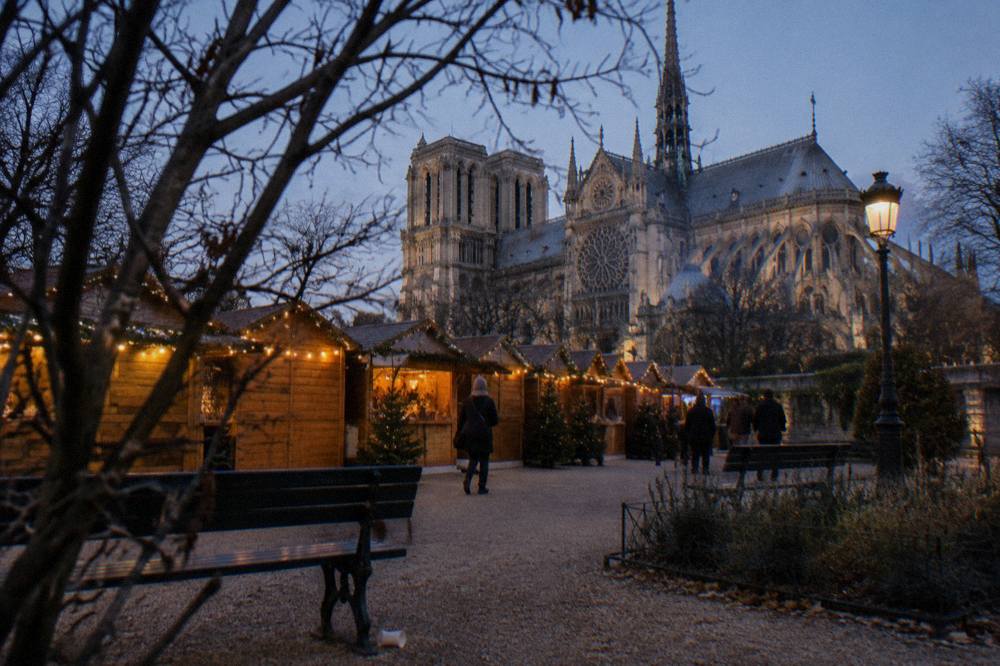 Festive wooden chalets with garlands on a wide Paris esplanade at night
