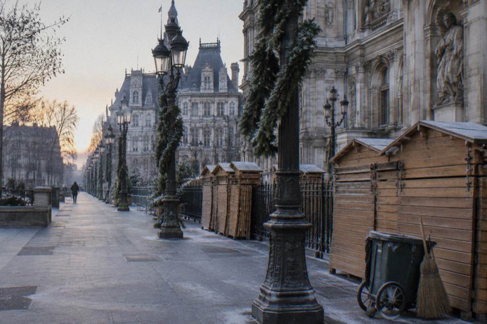A quiet Paris street corner with festive garlands and closed chalets waiting for the season