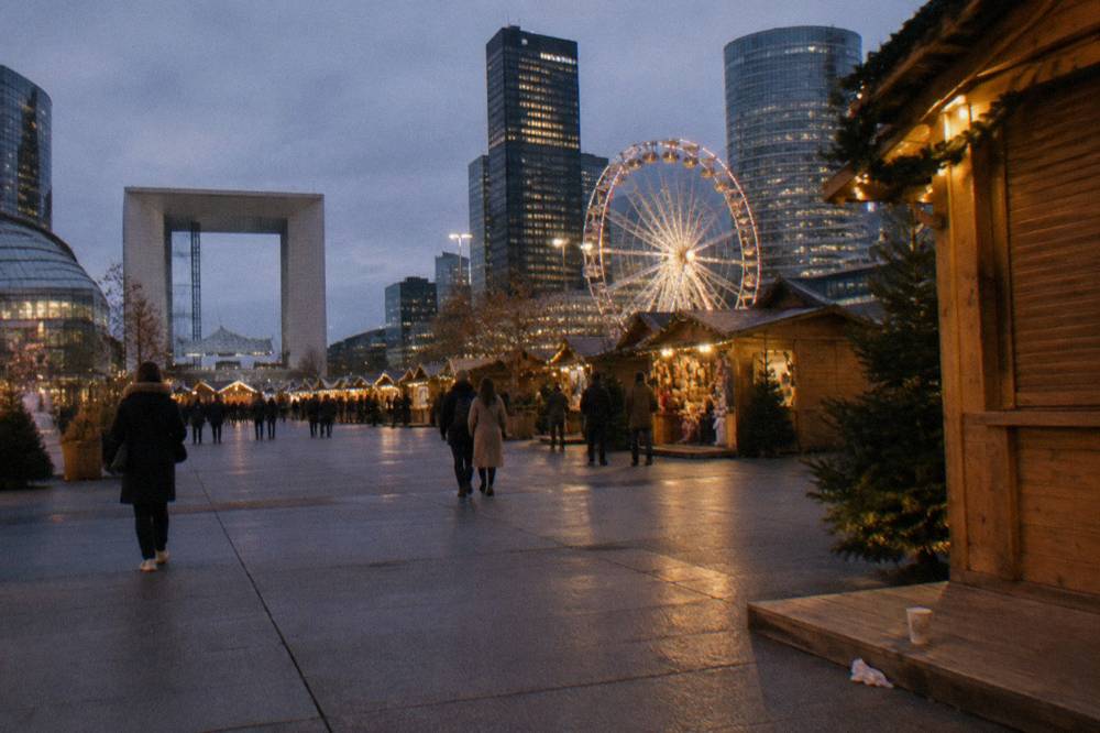 Christmas market chalets and a ferris wheel beside a river at dusk