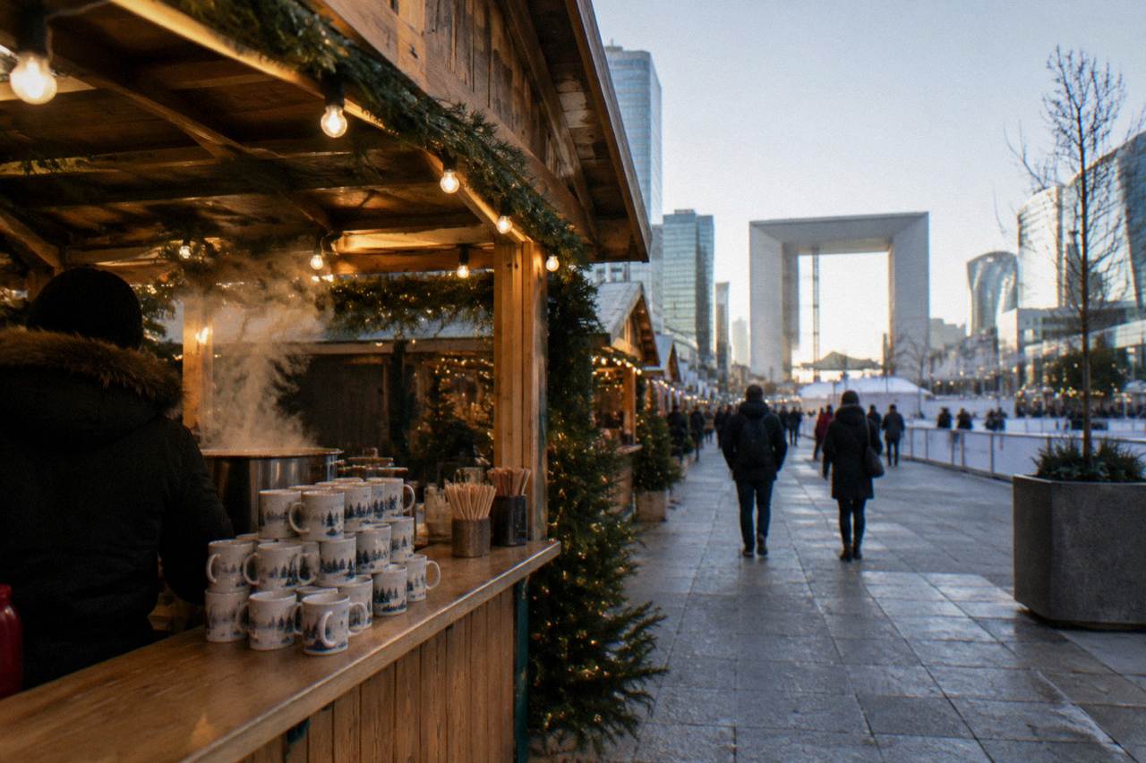 Wooden chalets of a Paris Christmas market strung with warm lights at dusk