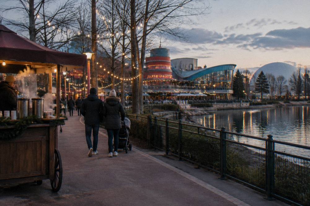 A decorated European theme park main street with Christmas garlands and a large tree
