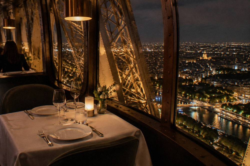 A festive restaurant table set beside a window with a night view over Paris
