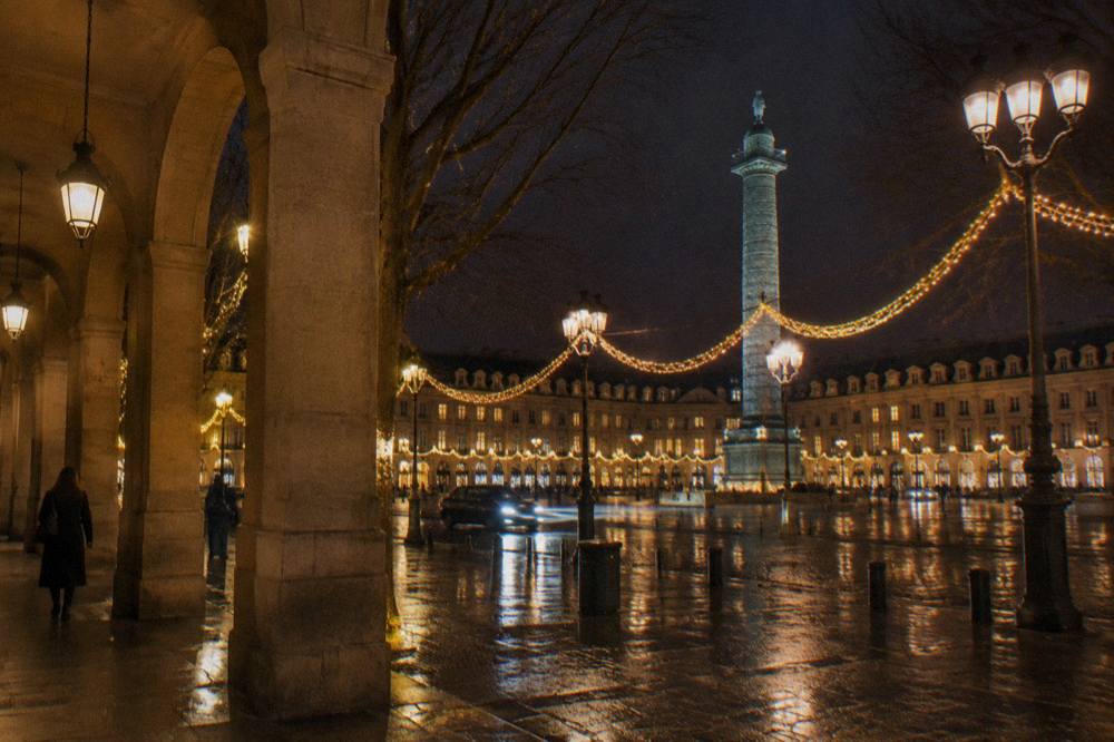 Golden Christmas garlands strung between trees along a wide Paris avenue at night