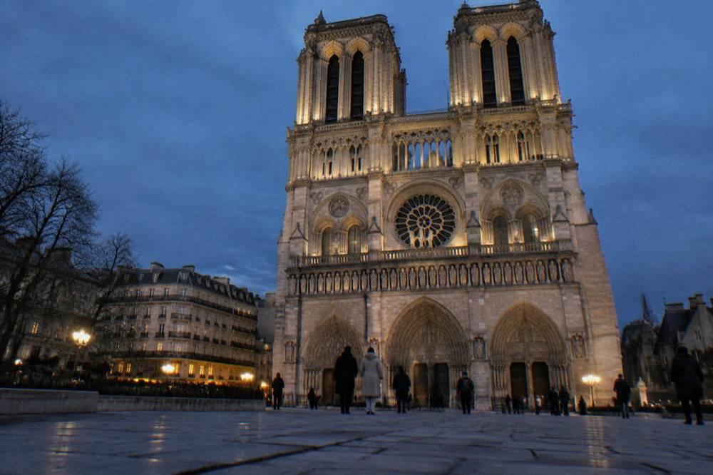 Gothic cathedral facade with twin towers seen from a square at dusk in winter