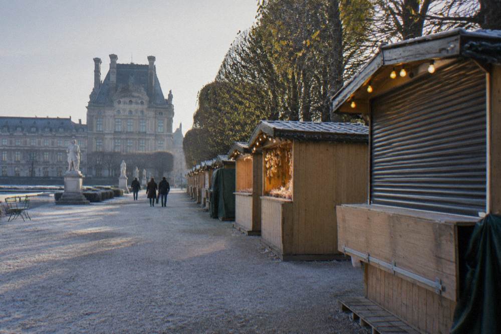 Wooden chalets of a Christmas market with warm lights along a stone terrace
