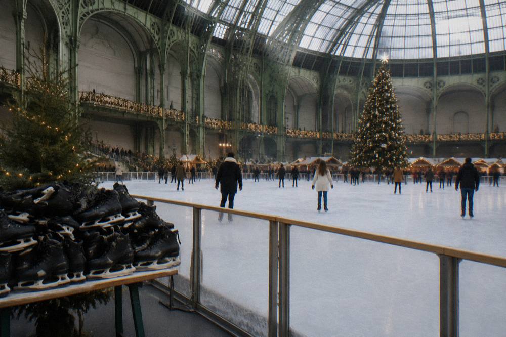 A wide ice rink set up inside a glass-roofed historic hall with festive lighting