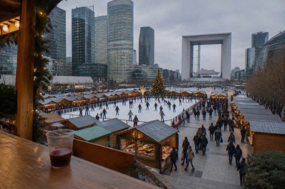 A Christmas market esplanade with wooden chalets and an ice rink in the middle