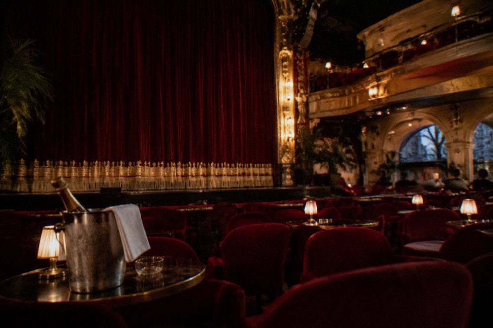 Cabaret hall interior with red velvet seats and a stage curtain before a show