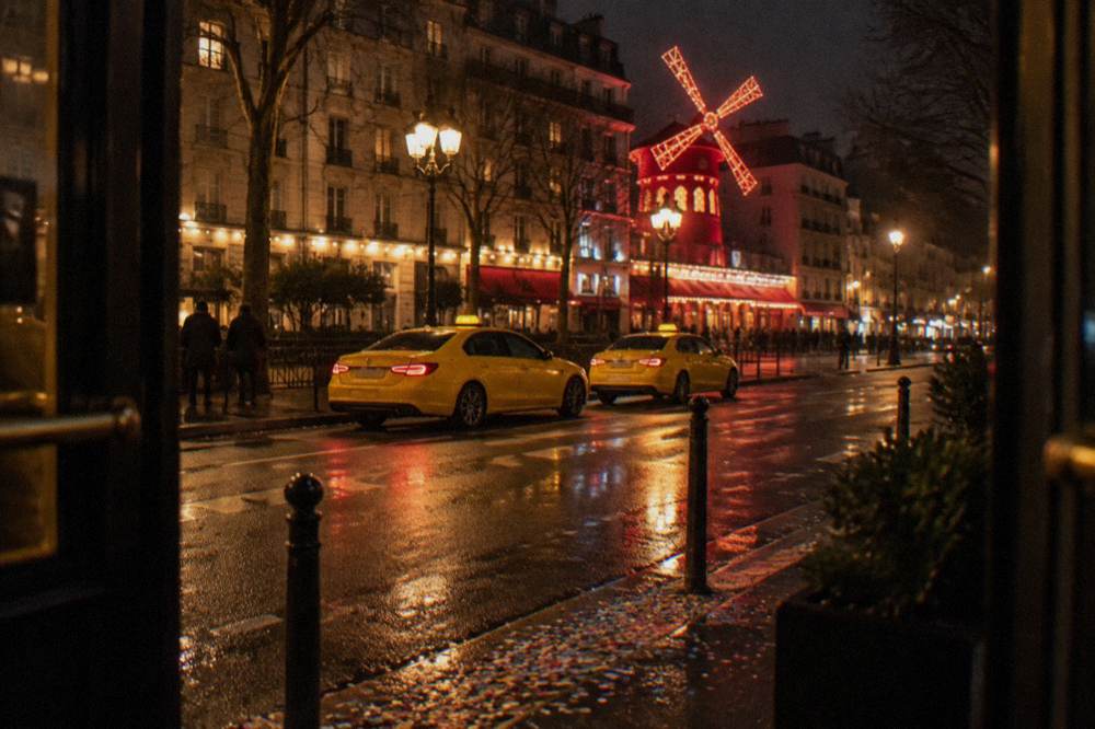 Illuminated Paris boulevard at night with theatre lights in the distance