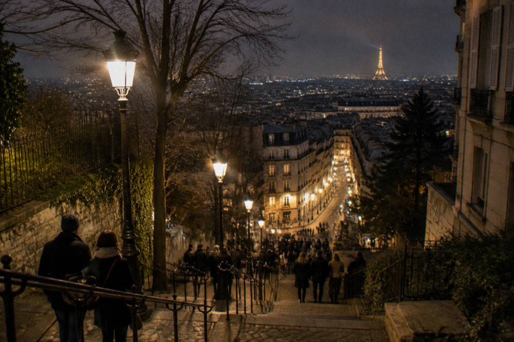 Night skyline of Paris with a lit boulevard and crowds gathering before midnight