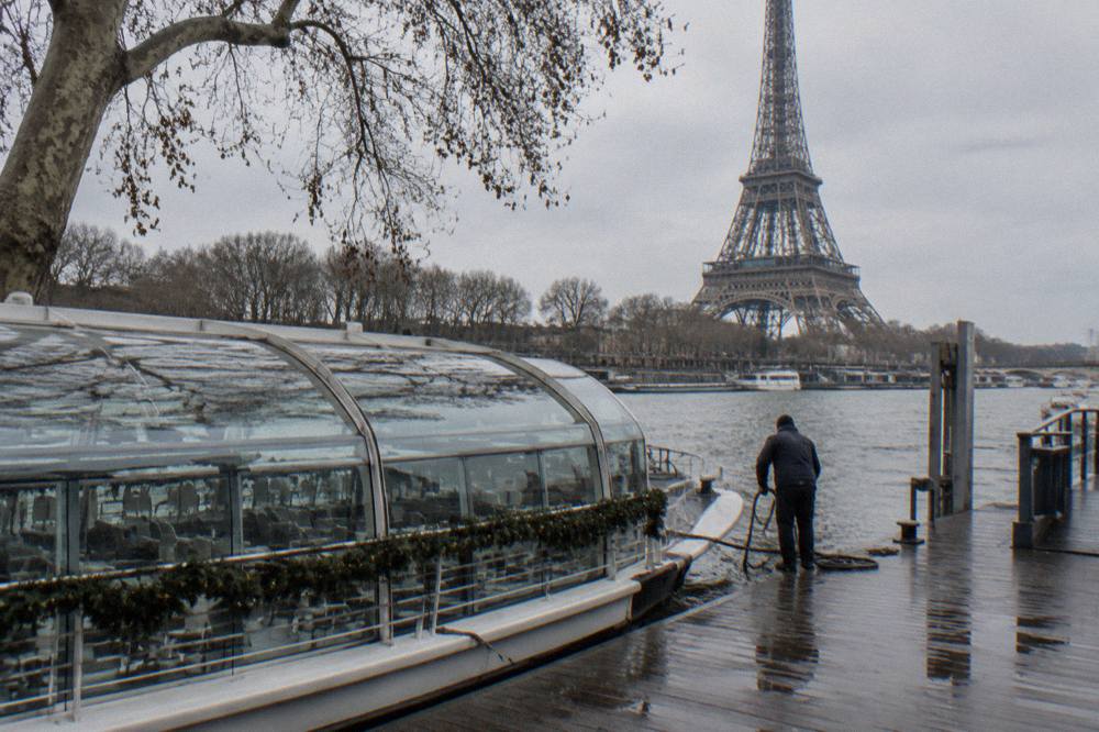 A glass-canopy boat moored on the Seine near the Eiffel Tower on a grey winter day