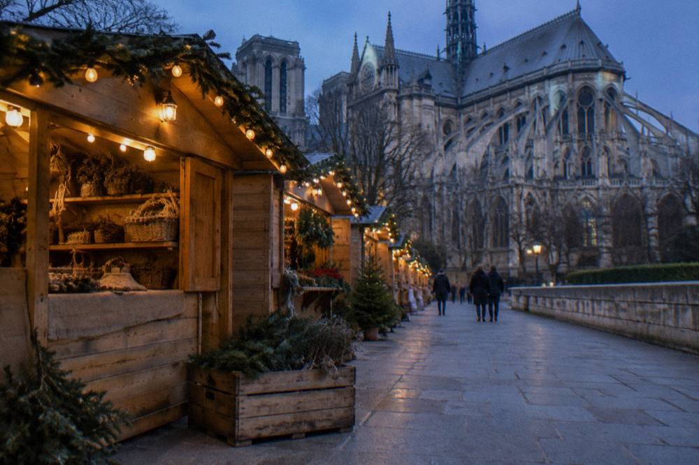 Festive chalets with glowing lights along a Paris esplanade in the evening