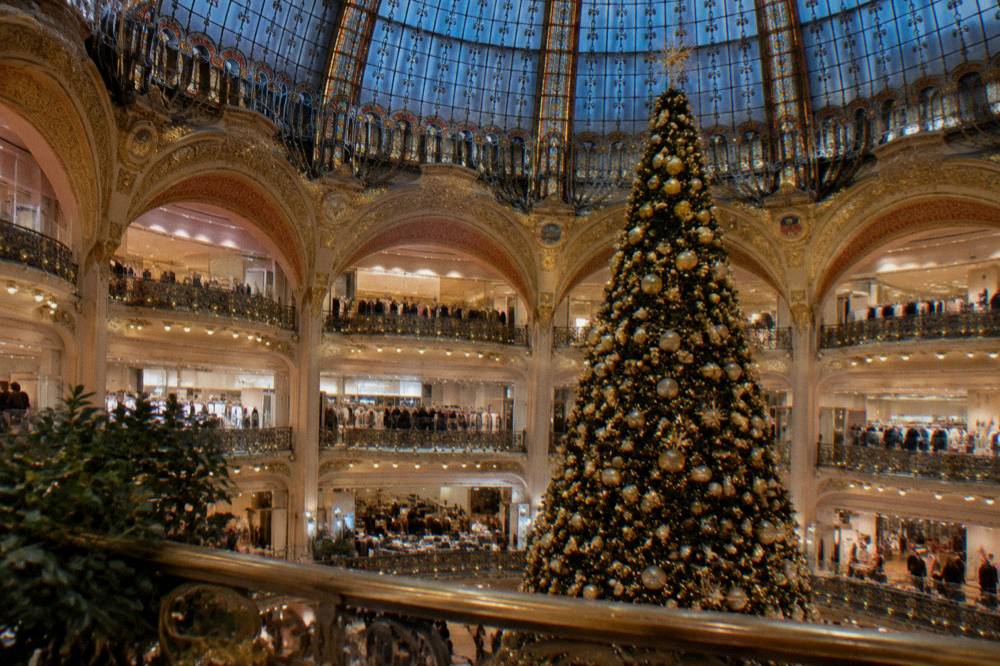 Market stalls and a giant illuminated tree in a Paris square after dark