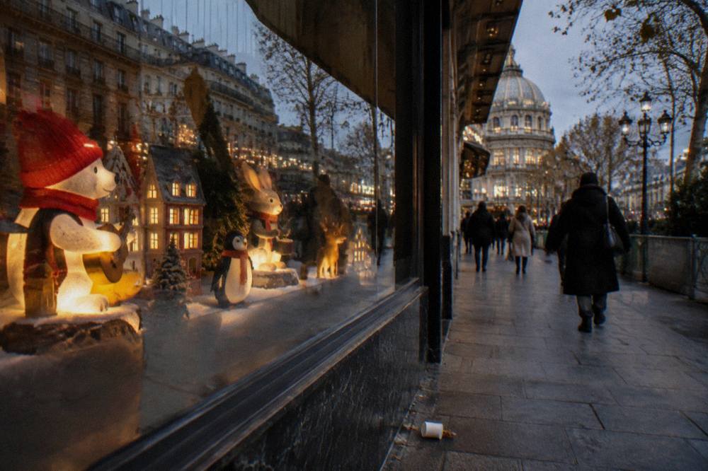 Festively decorated department store window display with illuminated figures behind glass