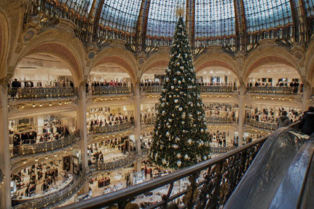 Ornate department store interior with a glass dome ceiling and a large illuminated Christmas tree