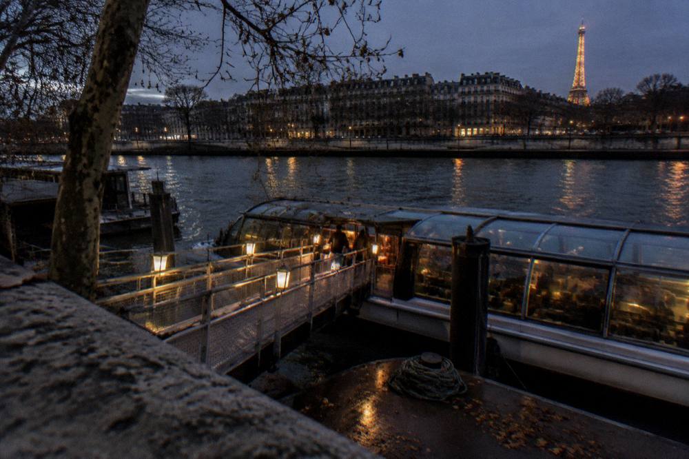 A boat pier at night with a gangway lit by lanterns and a dark river beyond