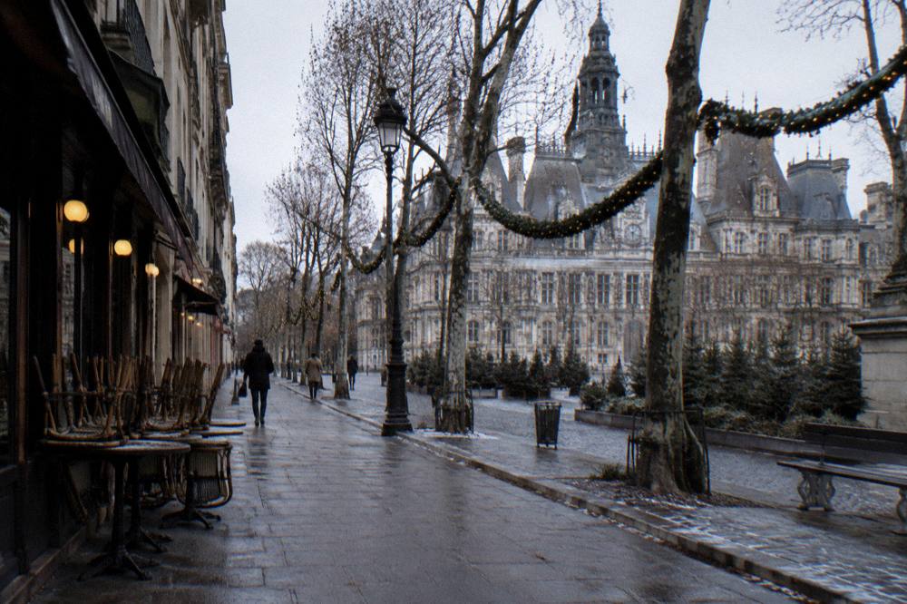 Quiet Paris street in winter with bare trees and holiday garlands between buildings