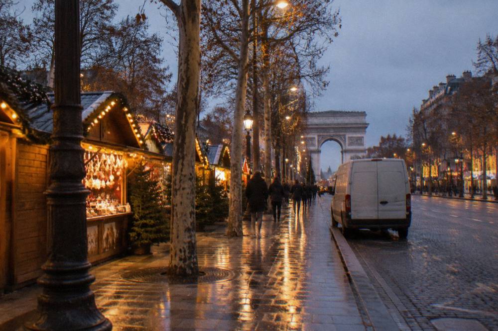 Illuminated Paris avenue at dusk with lights reflected on the pavement