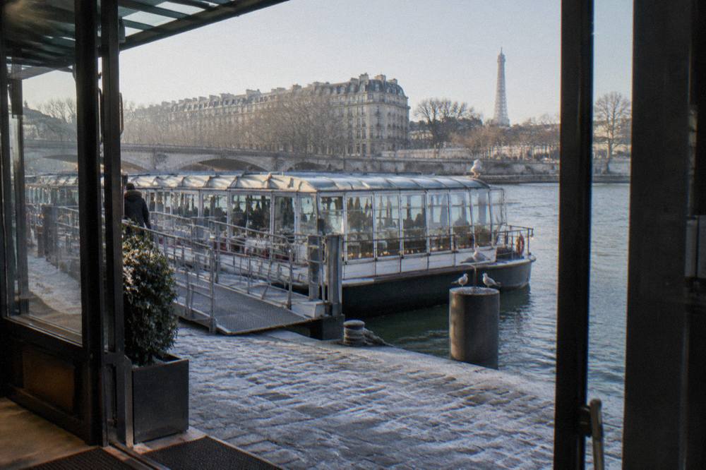 Glass-roofed dinner boat moored at a Seine pier with string lights along the deck