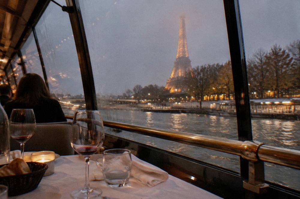 Set dinner table on a cruise boat with wine glasses and folded napkins beside a window
