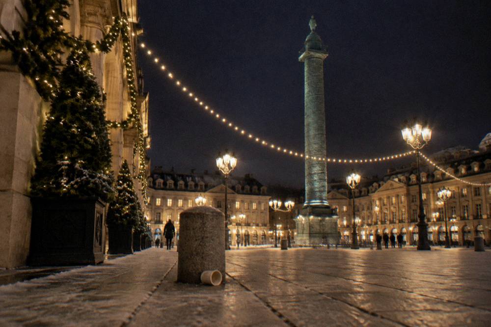Garlands of white lights stretching between trees along a wide illuminated avenue at night